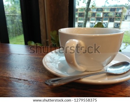 One white cup coffee on the wood table near window 