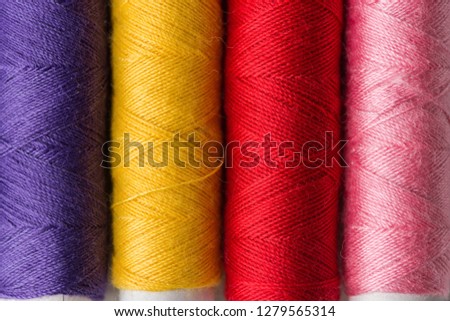 Row of multicolored rainbow palette sewing threads on cardboard spools. Crafts hobbies local artisan business interior decoration concept. Clean minimalist style copy space. Macro