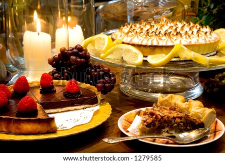 Chocolate Raspberry Torte, Lemon Meringue Pie, and Pecan Pie all surrounded by warm candlelit Kitchen.