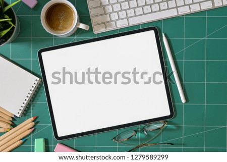 Mockup blank screen tablet and graphic designer supplies on green cutting mat