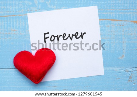 FOREVER word on paper note with red  heart shape decoration on blue wooden table background. Love, Wedding, Romantic and Happy Valentine’ s day holiday concept