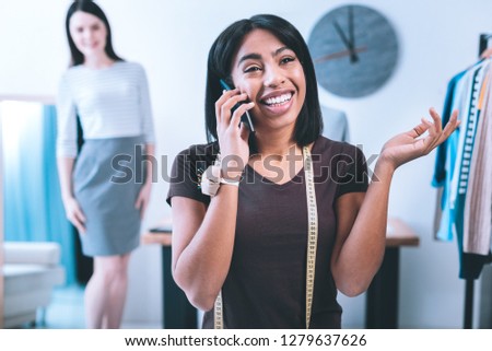 Feeling glad. Smiling nice girl talking on the phone telling about her new job