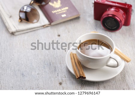 Coffee cup on wooden table on relaxing day to take pictures, with camera, passport and sunglasses.