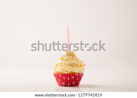 Cupcakes, pink and white Cupcake with pearl sprinkles and a candle isolated on white background, copy space