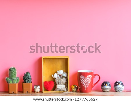 Valentine  concept  setting  with  cactus,red  heart,rose,cup  and  simulated  owl  on  wooden  surface  with  pink  background