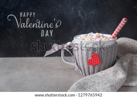 Hot chocolate with marshmallows, red heart on the cup on the table. Valentine's day background with text greeting