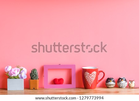 Valentine  concept  setting  with  rose 
 cactus,red  heart,cup  and  simulated  owl  on  wooden  surface  with  pink  background