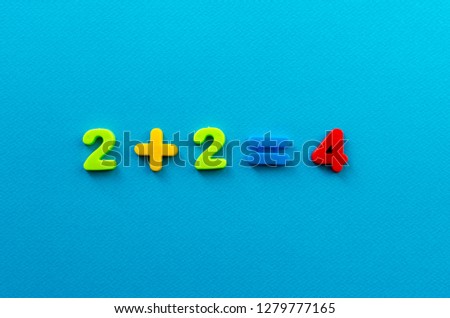 math action from colored plastic numbers on blue paper background