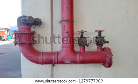 Red fire pump head valve, double head fire extinguisher brass valve, mounted on the wall for fire safety in buildings or various places on the background of building walls.