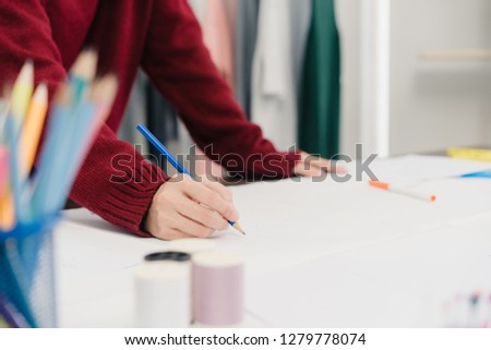 Professional beautiful Asian female fashion designer working with fabric sketches and drawing clothing design at the studio. Lifestyle women working concept.
