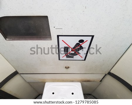 ‘Don’t stand on the toilet seat’ sign inside a dirty public toilet