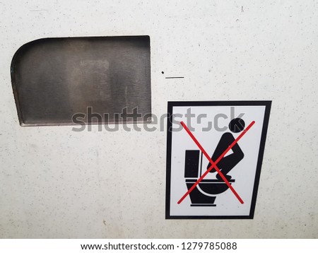 ‘Don’t stand on the toilet seat’ sign inside a dirty public toilet