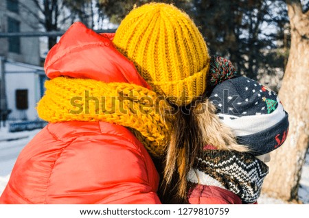 Winter season, snowing outside. Riding the sledge concept. A child with a woman are sitting on a sled. Moments spent with family in snow having fun.
