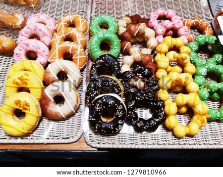 Picture of assorted donuts with chocolate frosted, pink glazed and sprinkles donuts.