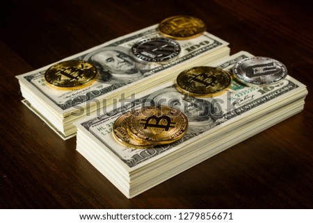 Cryptocurrencies in the form of coins on packs of dollars on a brown wooden table