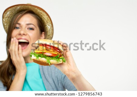 Happy girl holding big burger in front of face. Focus on burger.