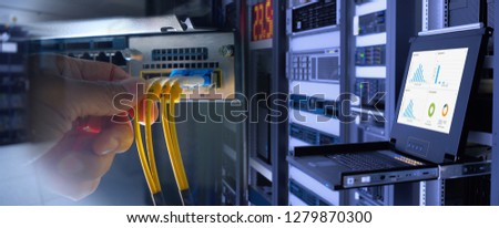 engineer and fiber optic cable on network router switch and monitor show graph information in background in technology data center room. widescreen Royalty-Free Stock Photo #1279870300