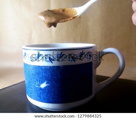 Its a picture of coffee cup pouring coffee cream in it.