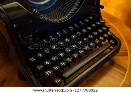 Old black typewriter with Russian Cyrillic letters on  wooden table, close up.