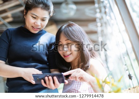 two beautiful asian woman friend happiness moment with selfie and enjoy conversation in coffeeshop with back window glass in garden