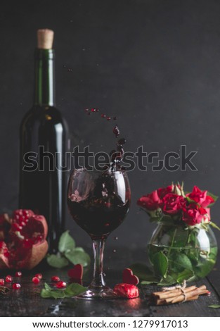 Red wine in a glass. Romantic evening with a glass of wine to Valentine's day.Holiday composition on a black table and background. Splash of drink