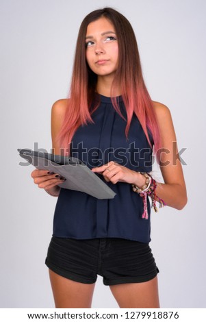 Portrait of young beautiful businesswoman thinking while using digital tablet