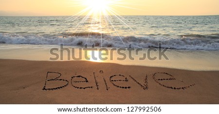 Believe written in the sand at the beach Royalty-Free Stock Photo #127992506