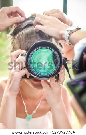The bride at the wedding with a camera in the hands of hairdressers fix her hair summer day