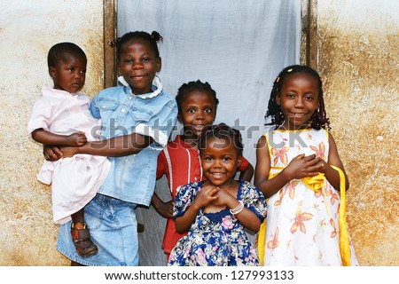 Real candid family photo of five cute and sweet black African sisters or girls, all smiling in their sunday dress, perfect for developing country and third world population issues.