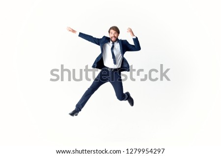 A man in a suit and tie bounces high, legs and arms bent                  
