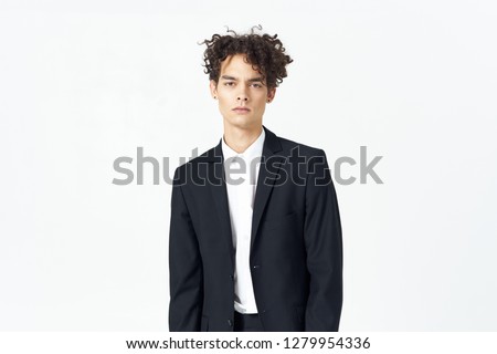 Business man in a dark suit with curly hair on a light background                    