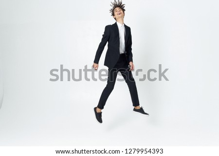 A man with curly hair in a dark suit bounces high               