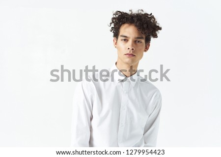 Curly man in a white shirt on a light background                       