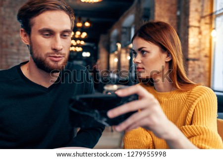 A woman shows a man a phone sitting in a cafe                    
