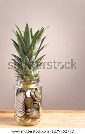 pennies in the glass bottle with pineapple leaf on the upside. Business and finance concept. copy space