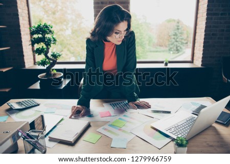 Close up photo of amazing attractive middle-aged she her lady look search learn notes in notebook business plan attentive table full of papers sheets in front of large windows wearing formalwear suit