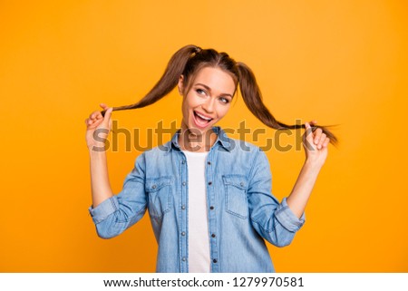 Portrait of nice cute lovely attractive adorable girlish cheerful cheery positive funny school girl  playing with curls opened mouth isolated over bright vivid shine yellow background