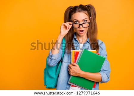 Portrait of her she nice adorable lovely attractive amazed positive school girl holding colorful copy-book putting glasses down off isolated over bright vivid shine yellow background