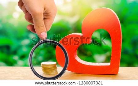 Red wooden heart and money. The concept of saving and accumulation money. Health charity. Donation. The purchases of Valentine's Day. Soft selective focus on the heart.