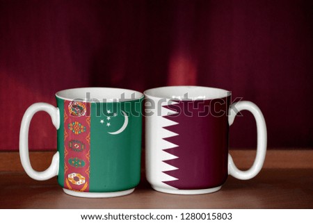 Qatar and Turkmenistan flag on two cups with blurry background