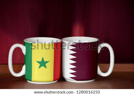 Qatar and Senegal flag on two cups with blurry background