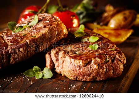 Close up of a rare roasted juicy medallion of beef fillet seasoned with salt and spices and garnished with fresh herbs served on a wooden board Royalty-Free Stock Photo #1280024410