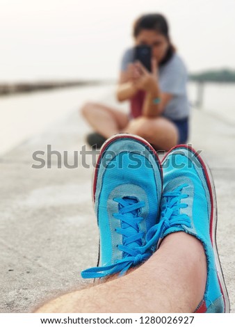 The woman is taking picture of blue sneakers