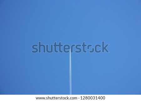 immense clear blue sky furrowed by the wake of an airplane