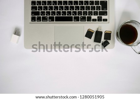 White Working table desk with laptop smartphone coffee mug memory card on white background. Flat lay, top view, copy space