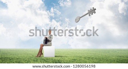 Elegant businesswoman with suitcase in hand sitting on white cube and stone key symbol