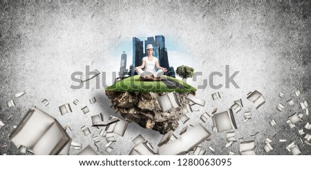Woman in white clothing keeping eyes closed and looking concentrated while meditating on island in the air among flying books with gray wall on background. 3D rendering.