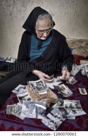 Nostalgic old woman looking at vintage photos