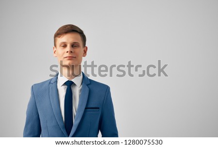Smiling business man in a jacket with a tie on a gray background                  