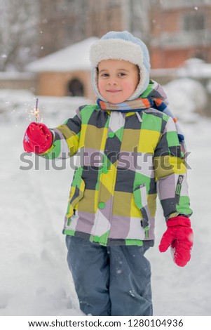 the little boy is standing on the street with sparklers. Happy baby with sparkler. vertical photo.
